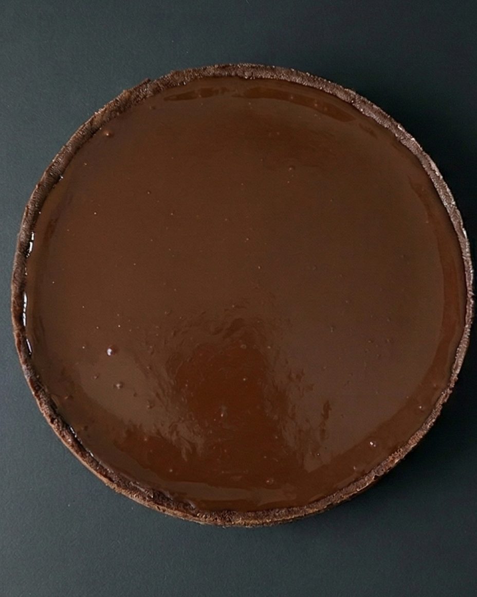 Cheesecake Chocolate Marble entier vu de dessus, avec un dessus de chocolat brillant et des copeaux de chocolat