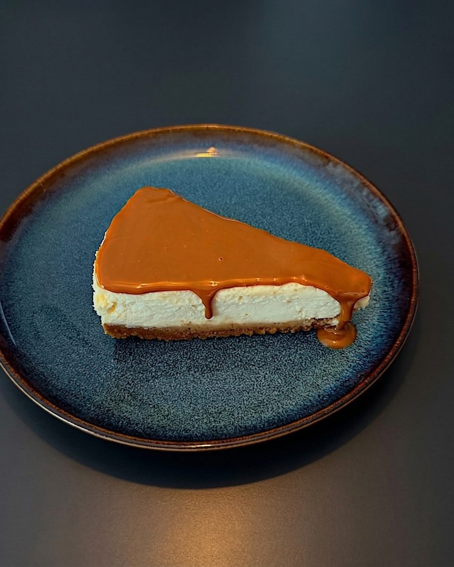 A slice of Lotus New York cheesecake with speculoos topping on a dark blue plate